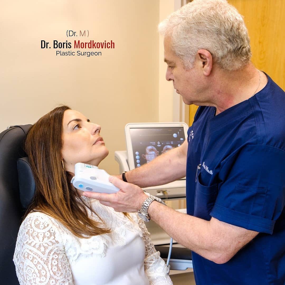 Dr. Boris Mordkovich consulting with a patient using an ultrasound device for skin tightening assessment